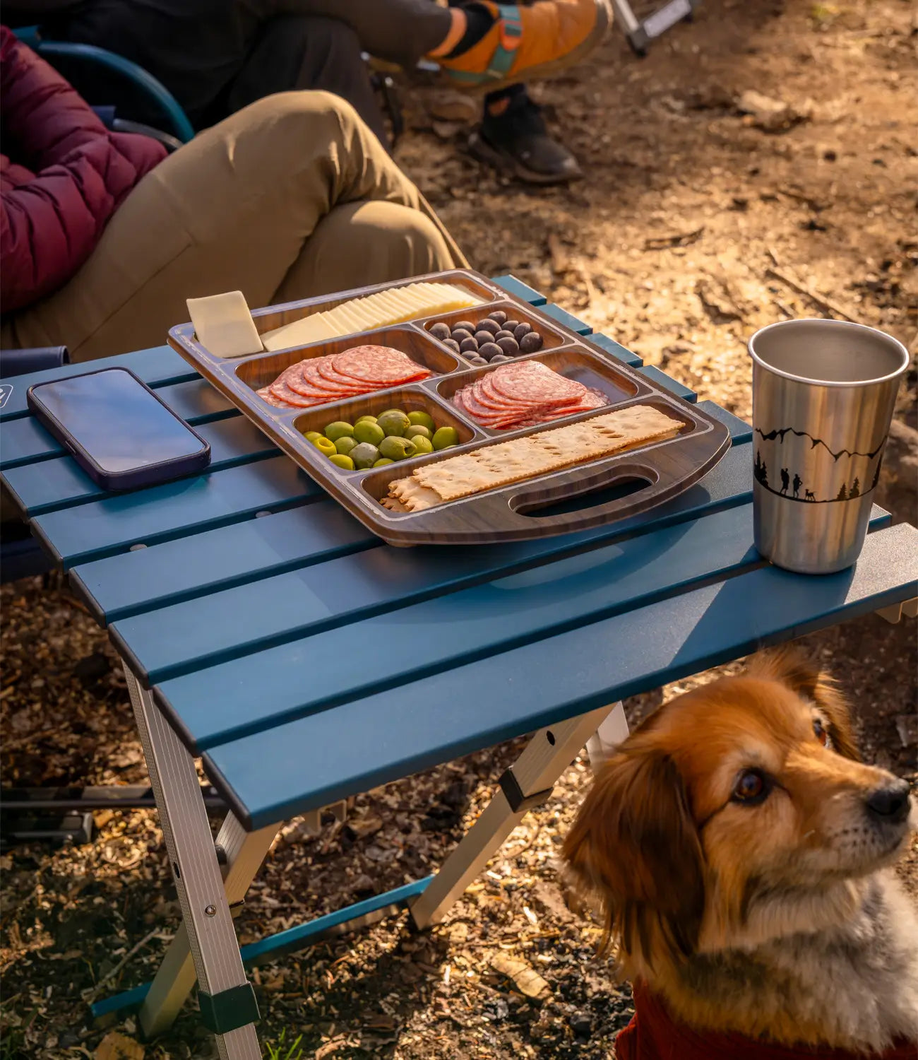 A dog sitting next to an indigo Compact Table. 