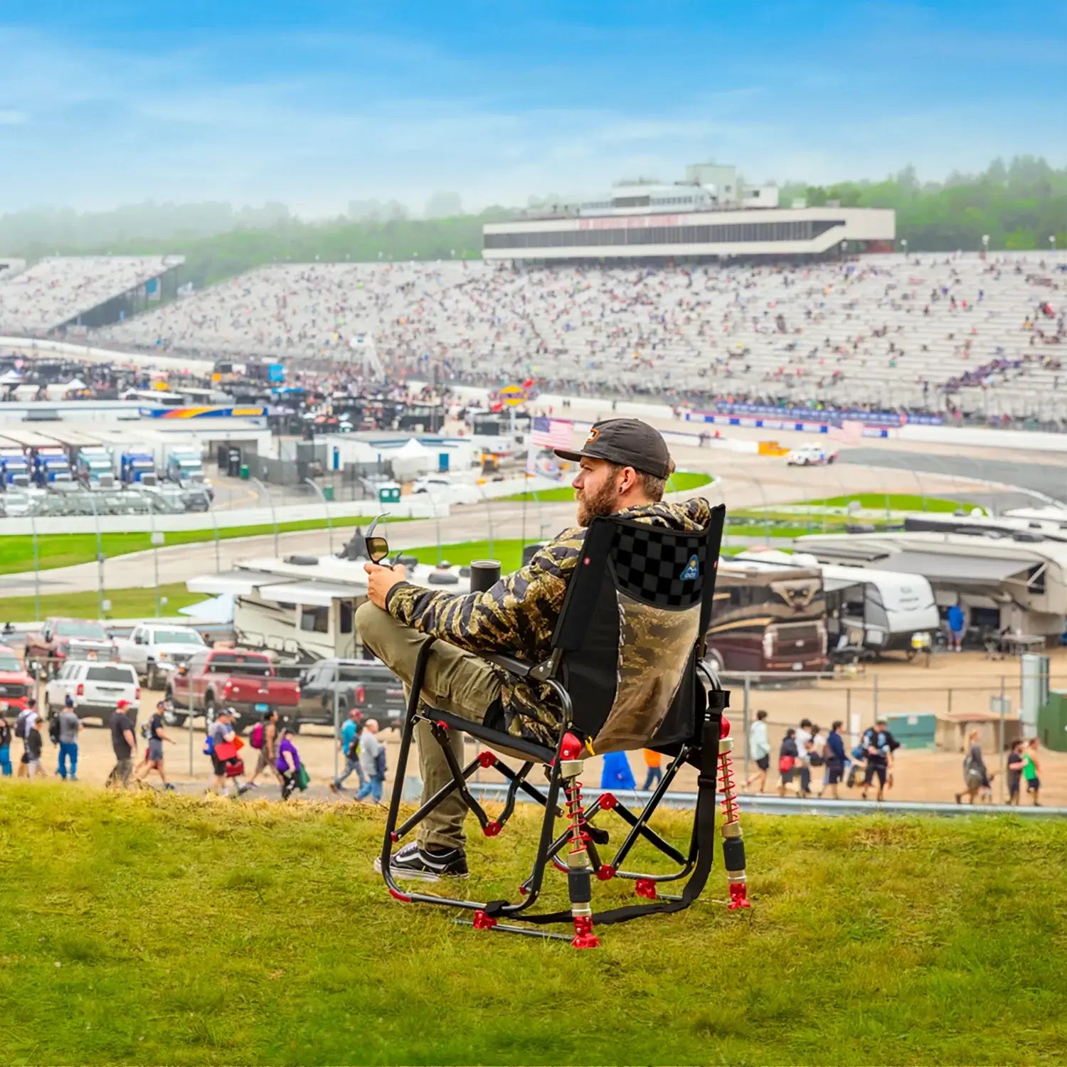 A man sitting in a NASCAR themed Adjustable Rocker while overlooking a race track. 