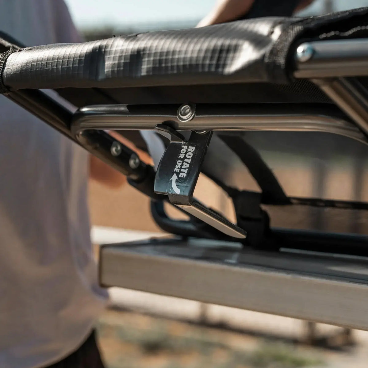 Close-up of the L-hook mechanism on a Big Comfort Stadium Chair 2.0, rotated into place to secure the chair beneath a bleacher bench.