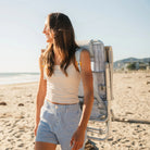 Woman walks along the beach with a GCI Big Surf with Slide Table in light blue mosaic worn backpack-style.