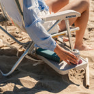 Close-up of the Slide Table on a GCI Big Surf chair in retro beach stripes, holding a book and a canned drink in the cupholder.