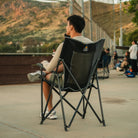 A man sitting in a black Eazy Chair XL watching a baseball game. 