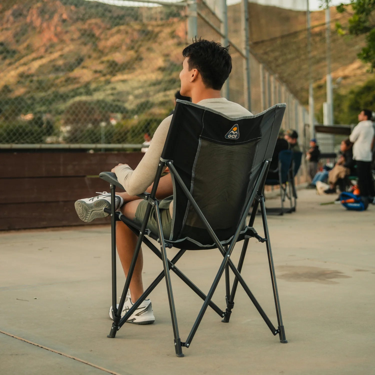 A man sitting in a black Eazy Chair XL watching a baseball game. 