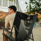 A man sitting in a black Eazy Chair XL watching a baseball game. 
