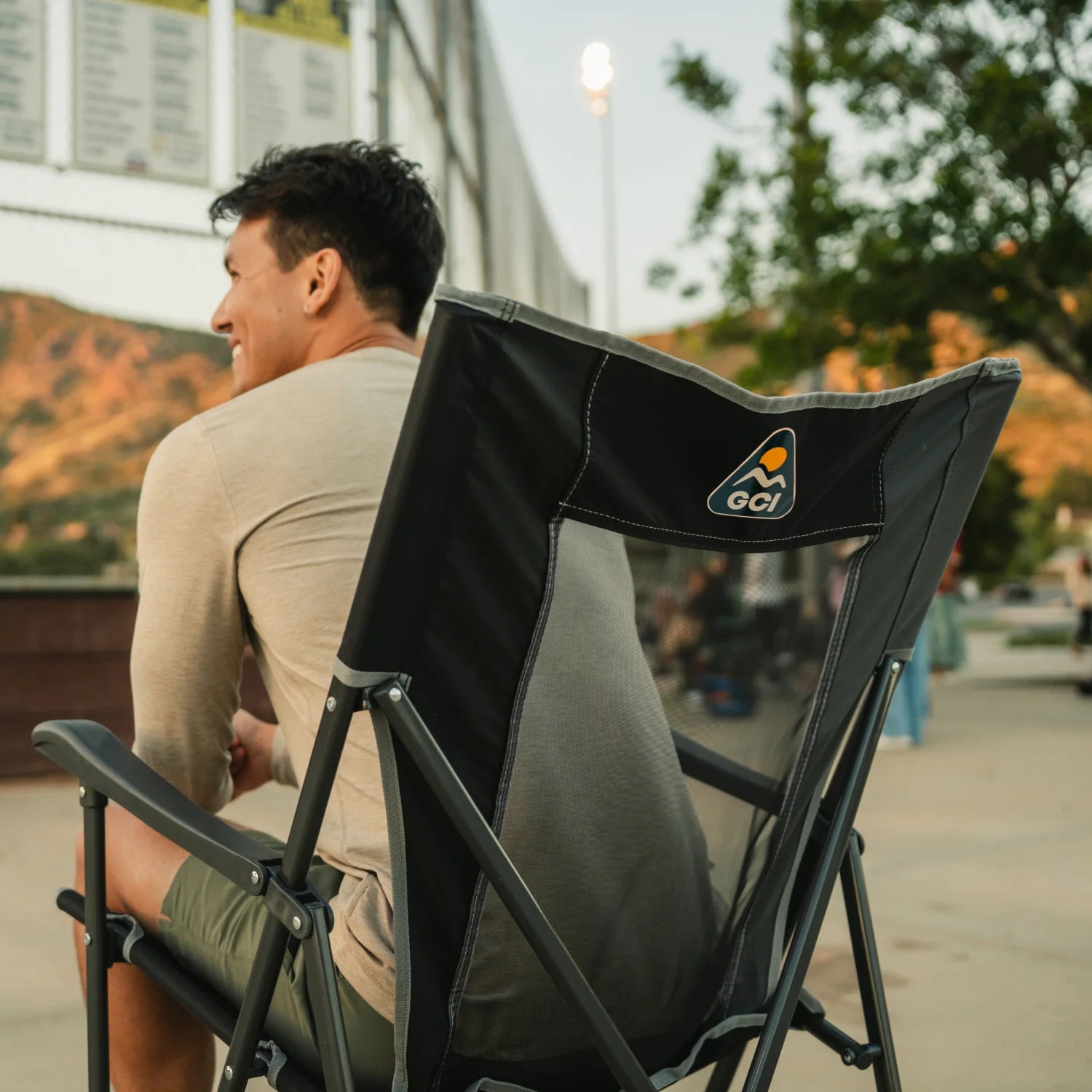 A man sitting in a black Eazy Chair XL watching a baseball game. 