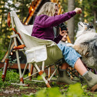 Woman leans out of a natural Fleece Rocker to give the dog beside her a treat.