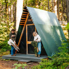Man and woman unfolding their Fleece Rockers outside an A-frame cabin in the woods.