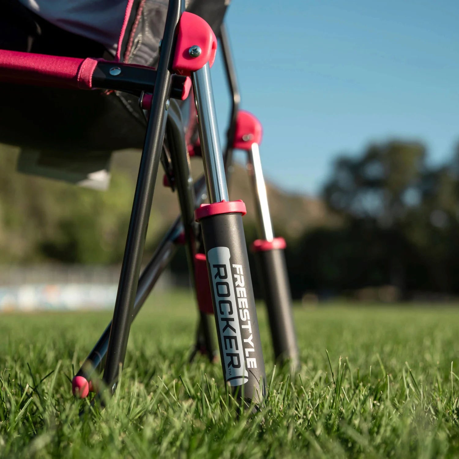 Close-up of the rocking legs on a pink shockwave Freestyle Rocker, set on a grass field.