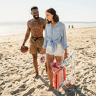 A man and woman walking together on a beach while the woman carries a Grab and Go Rocker. 