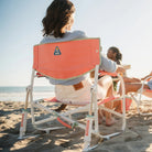 A woman sitting on a beach in a Grab and Go Rocker while reading a book. 