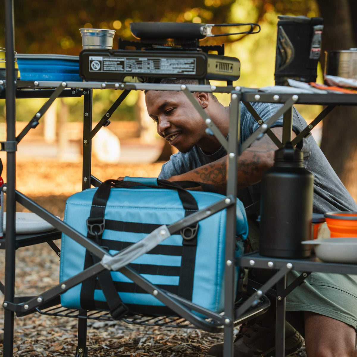 A man unpacking a bag being held on the bottom of the Master Cook Station. 