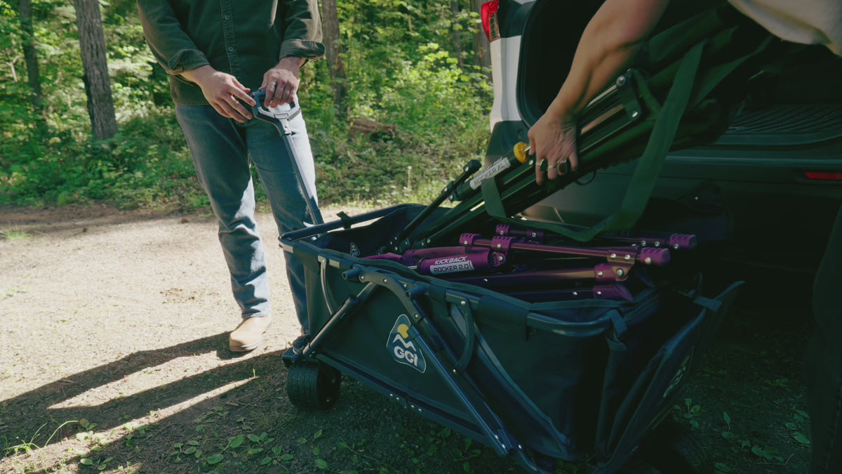 A group of people hauling their GCI Outdoor chairs using their Go-Hauler wagon and traveling to a campsite. 