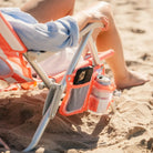 Close-up of a coral-striped GCI SideKick beach chair side pocket holding a phone and drink can.