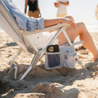 Close-up of the SideKick beach chair's armrest pocket holding a phone and drink can.