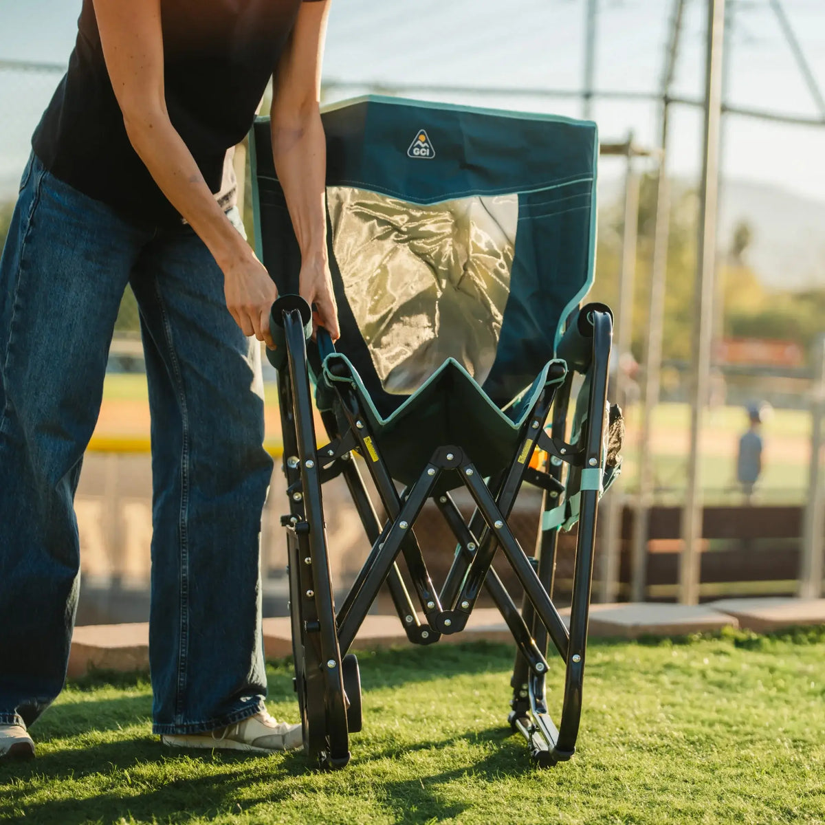 A person unfolding a teal Stowaway Rocker with Side Table. 