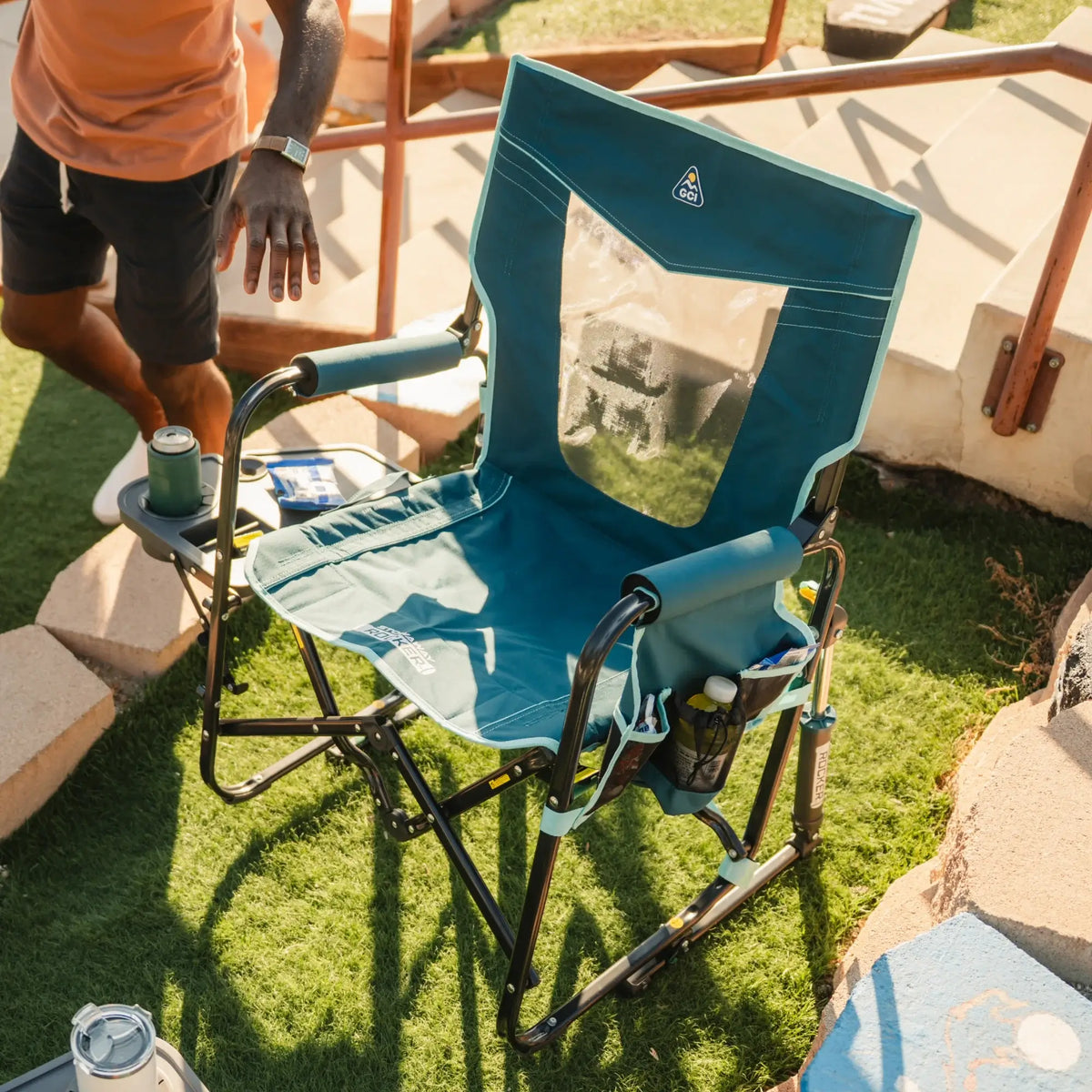 A full view of the teal Stowaway Rocker with Side Table positioned next to another GCI chair. 