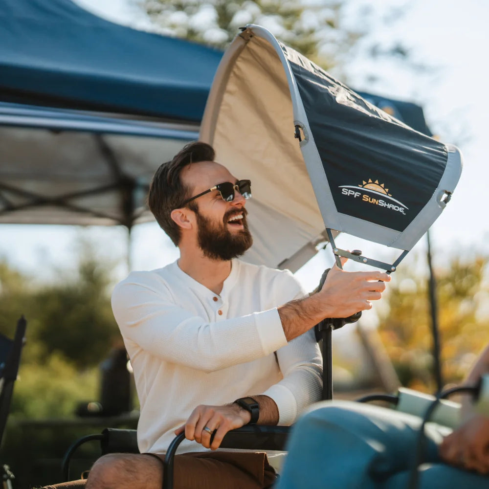 Person attaching a SunShade Accessory to a folding chair, adding extra sun protection for outdoor relaxation.